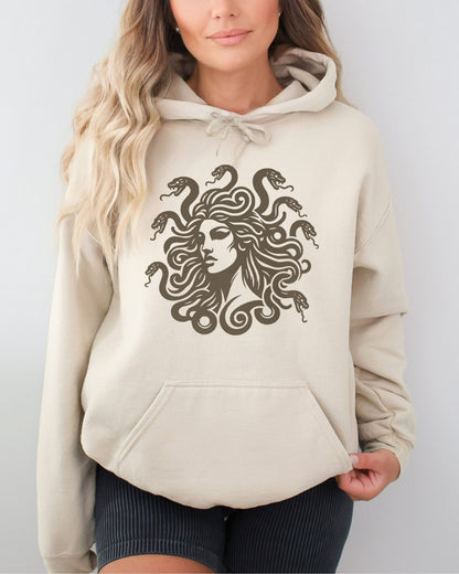 Woman wearing a sand beige hoodie featuring a vintage-style Medusa graphic with snake hair.