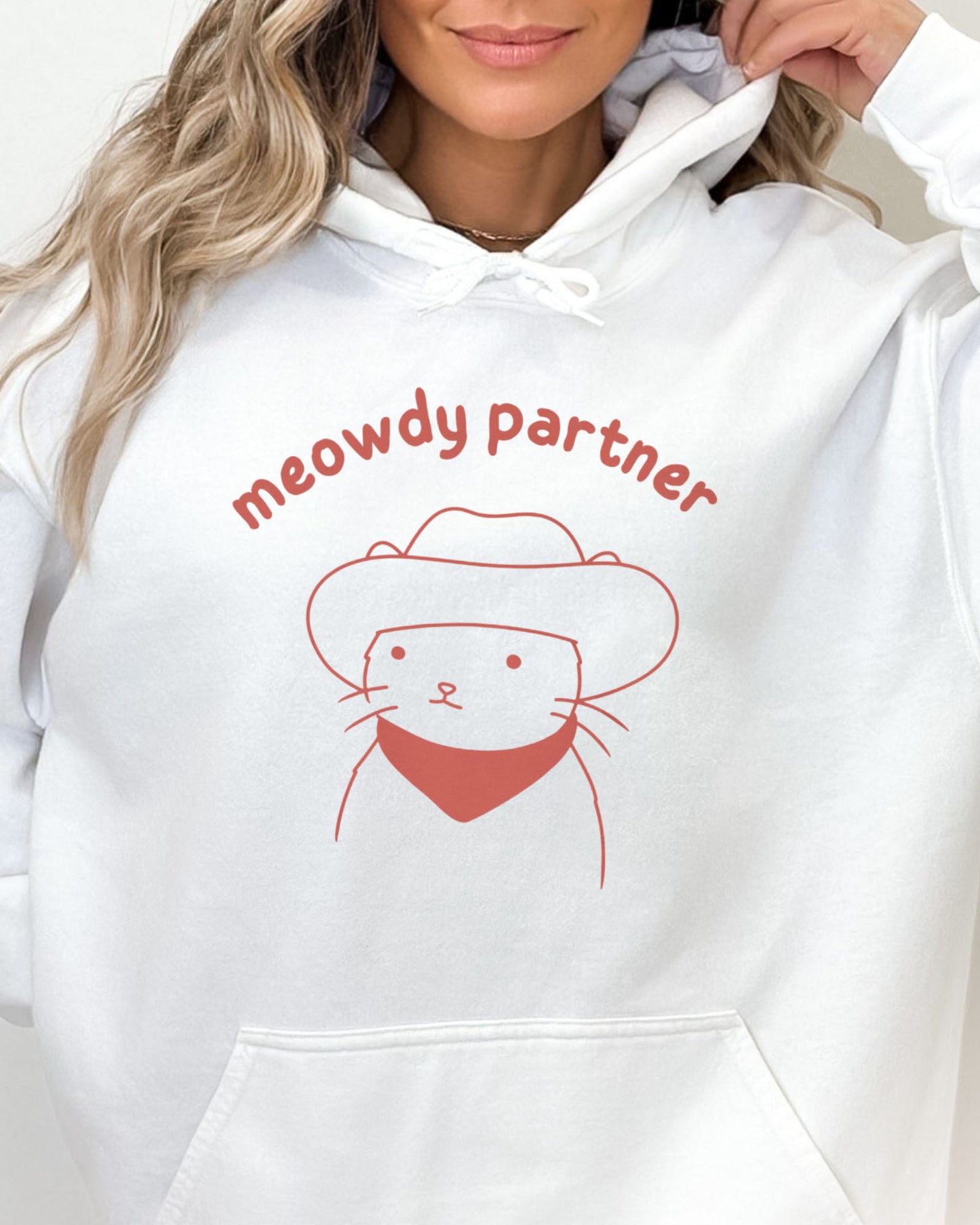 Close-up of a white hoodie featuring a funny retro cowboy cat line-art graphic with the quote 'Meowdy Partner'.