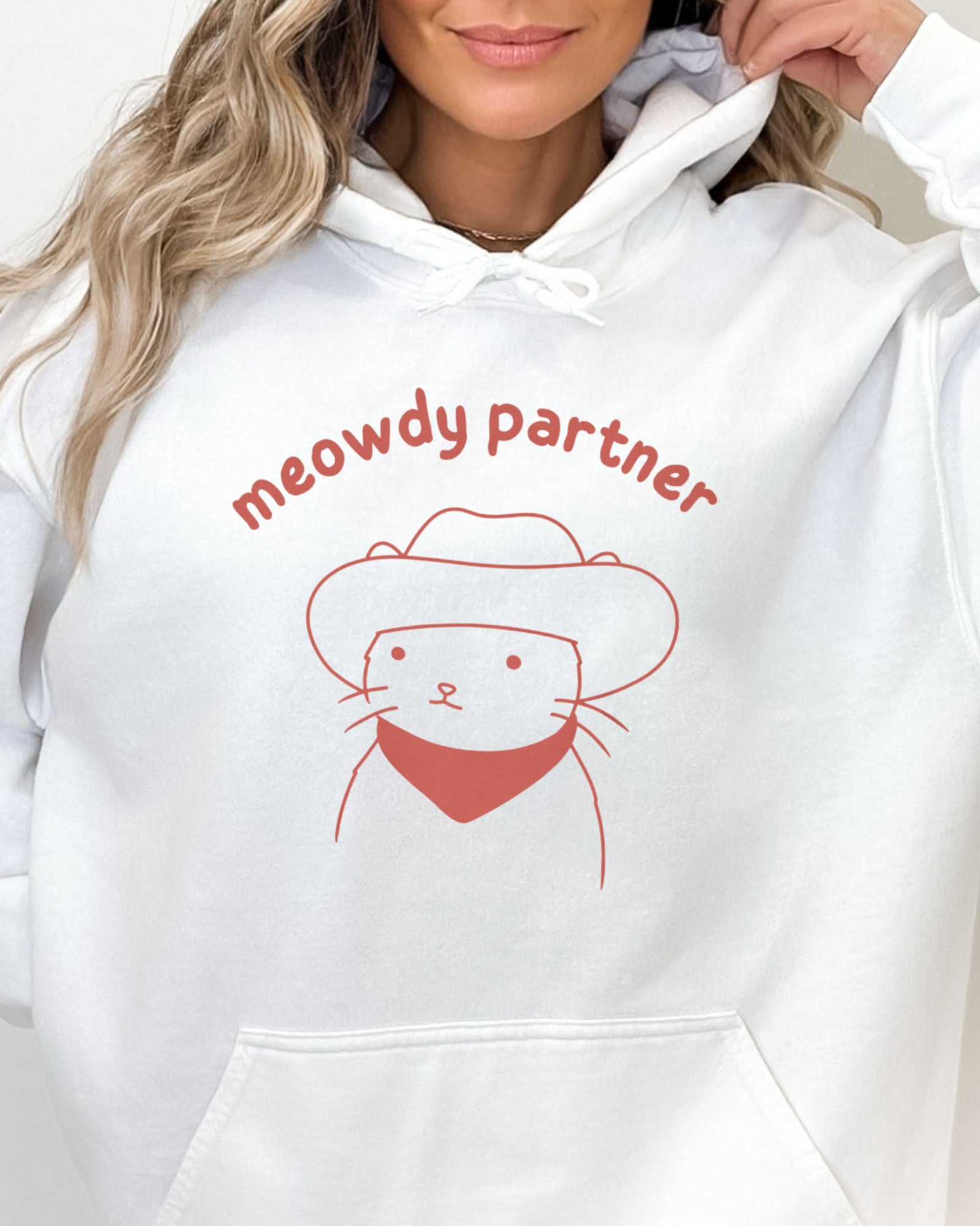 Close-up of a white hoodie featuring a funny retro cowboy cat line-art graphic with the quote 'Meowdy Partner'.