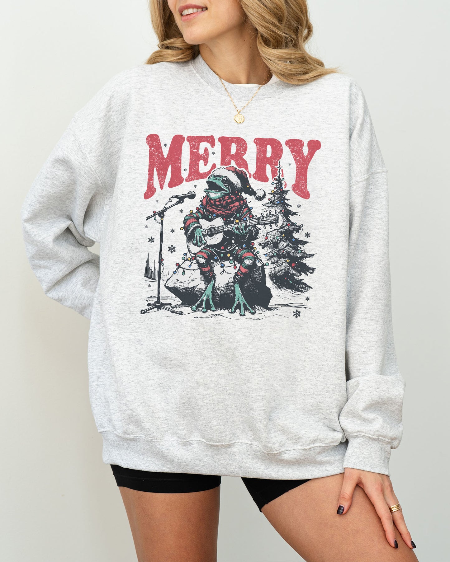 Model wearing ash color sweatshirt with 'Merry Frog' graphic design