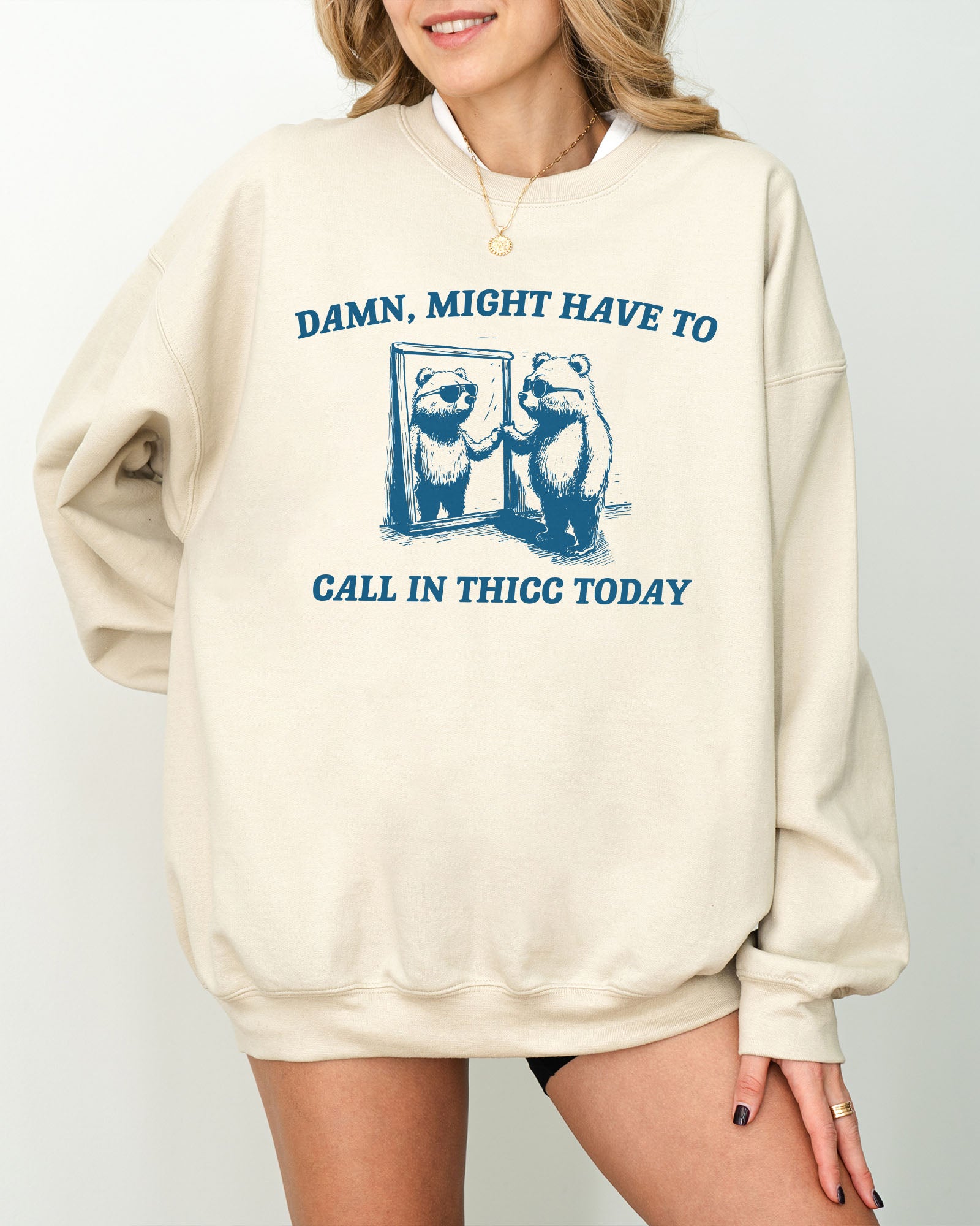 Model wearing sand color sweatshirt with 'Damn, Might Have To Call in Thicc Today' graphic design