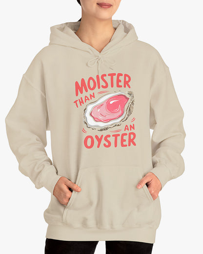 Woman wearing a sand beige 'Moister Than An Oyster' hoodie featuring a funny oyster graphic.