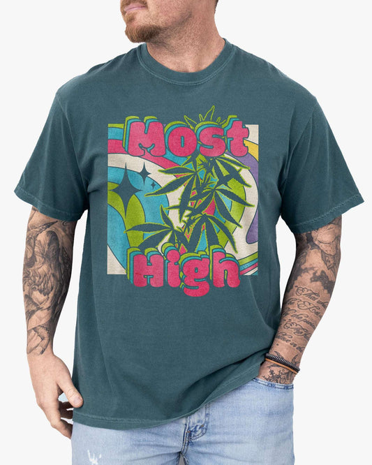 Man wearing a blue spruce-colored ‘Most High’ shirt with a retro multicolor trippy collage graphic of cannabis plants.