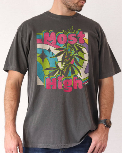 Man wearing a pepper-colored ‘Most High’ shirt with a retro multicolor trippy collage graphic of cannabis plants.