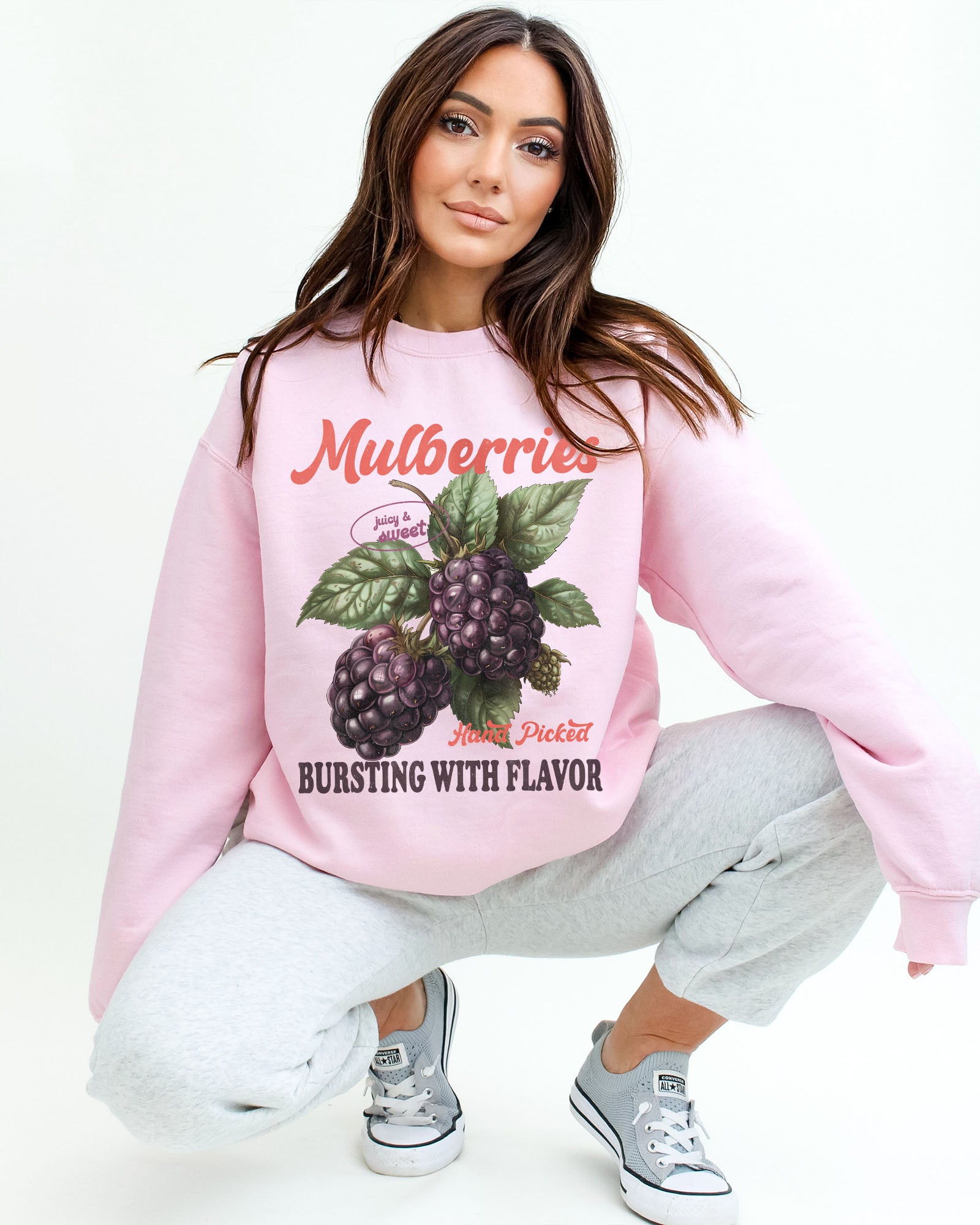 Model wearing light pink color sweatshirt with mulberries fruit graphic design