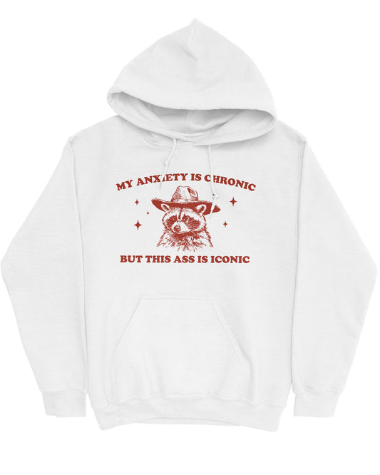 Flat lay of a white 'My Anxiety Is Chronic But This Ass Is Iconic' hoodie featuring a funny retro cowboy raccoon graphic.