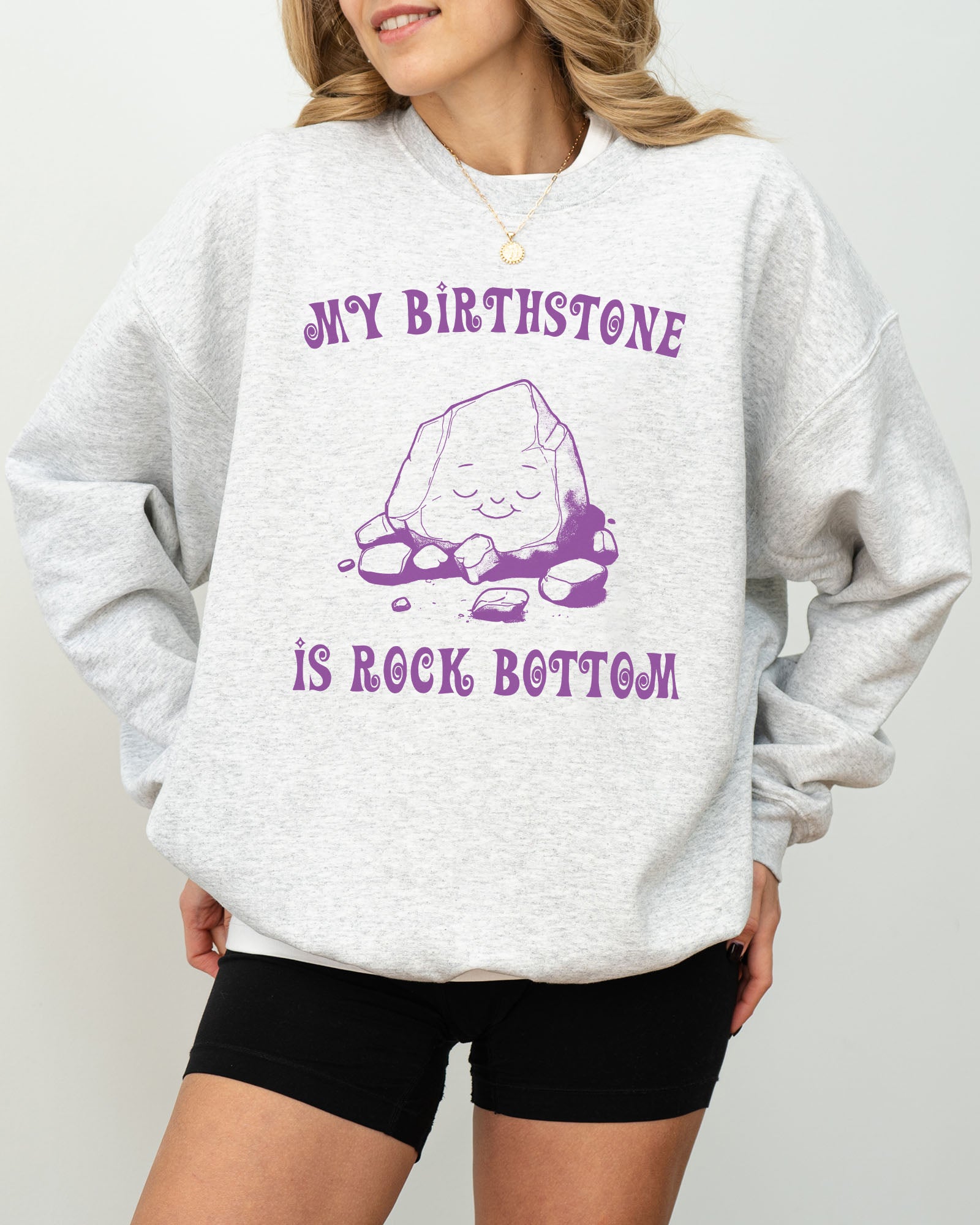 Model wearing ash color sweatshirt with 'My Birthstone Is Rock Bottom' graphic design