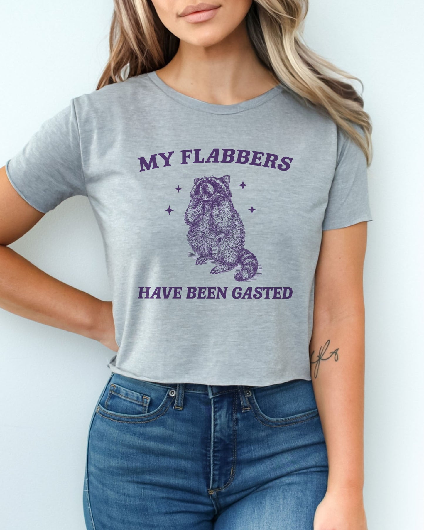 Woman wearing dark heather 'My Flabbers Have Been Gasted' crop top featuring a funny retro raccoon freaking out graphic.