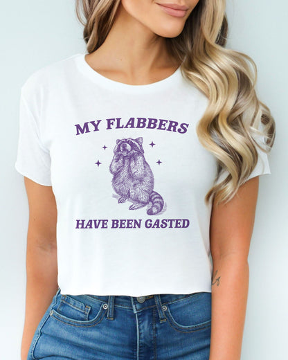 Woman wearing white 'My Flabbers Have Been Gasted' crop top featuring a funny retro raccoon freaking out graphic.
