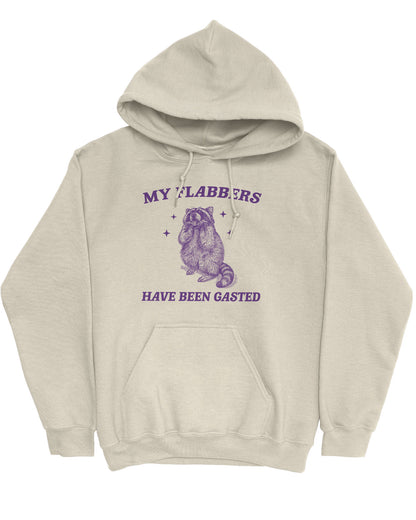 Flat lay of a sand beige 'My Flabbers Have Been Gasted' hoodie featuring a funny retro raccoon freaking out graphic.