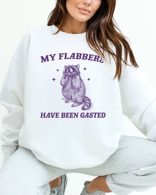 Woman wearing a white sweatshirt with a funny retro flabbergasted raccoon graphic and the quote 'My Flabbers Have Been Gasted'.