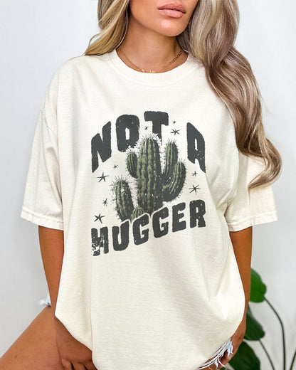 Model wearing natural color shirt with 'Not A Hugger' cactus graphic design