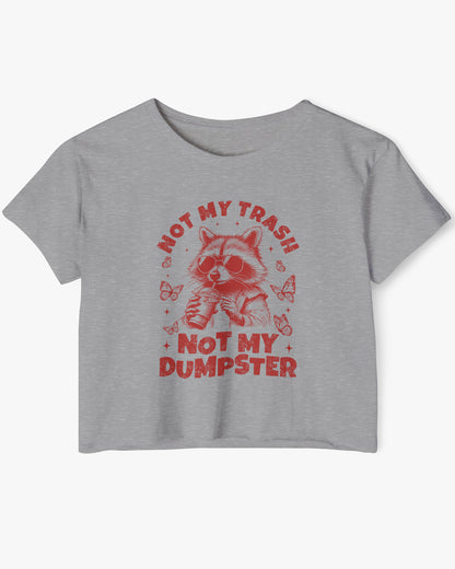 Flat lay of a heather gray 'Not My Trash Not My Dumpster' crop top featuring a funny retro raccoon drinking coffee graphic.