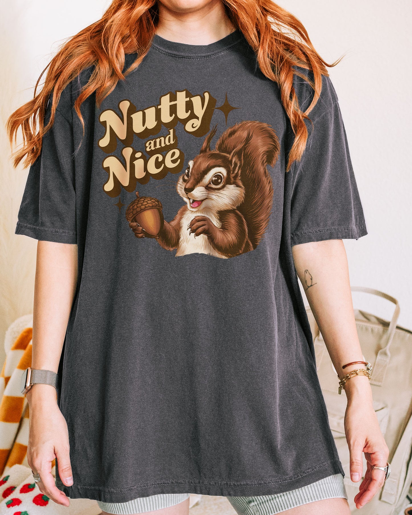 Woman wearing a pepper-colored ‘Nutty and Nice’ shirt with a retro graphic of a squirrel.