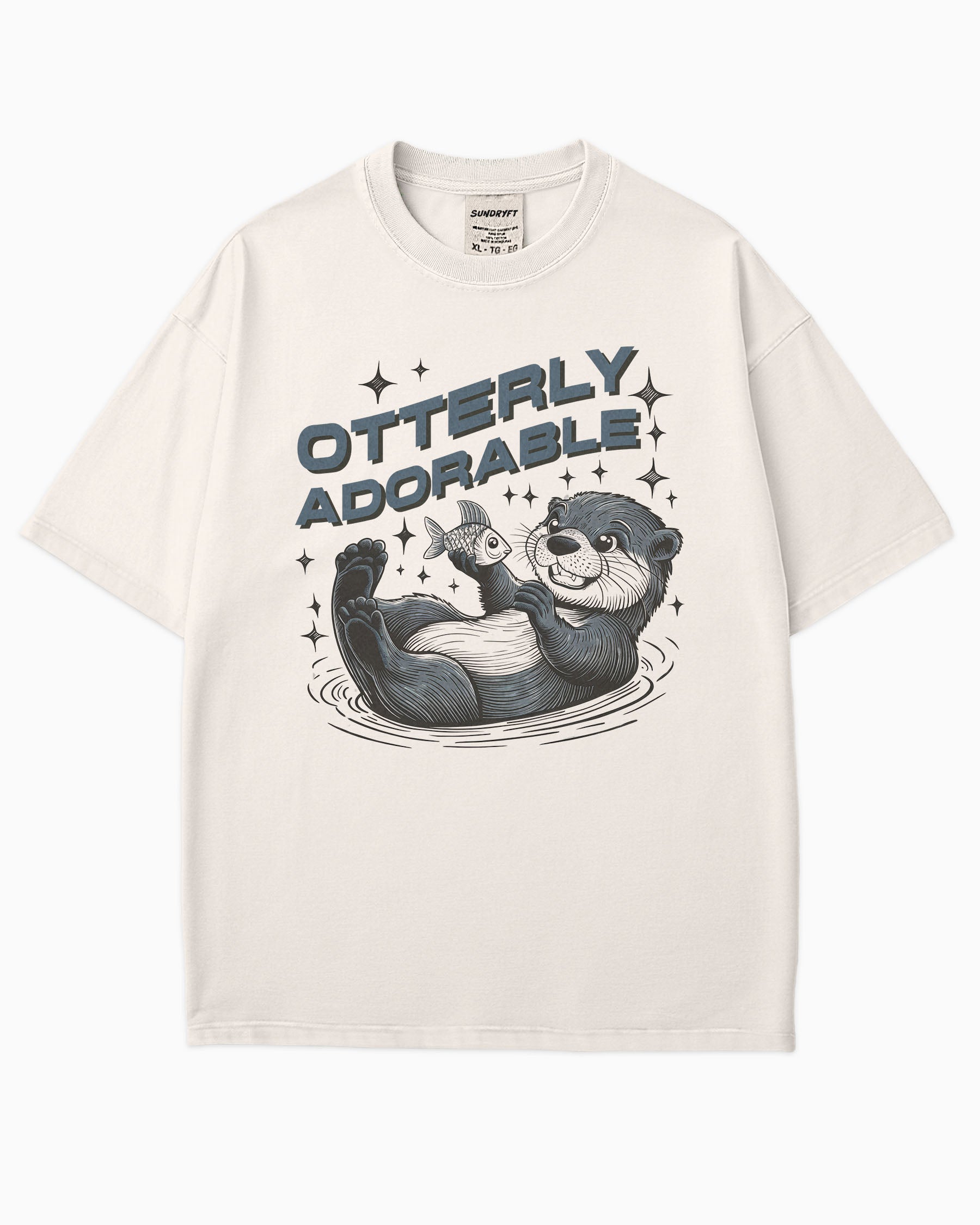 Flat lay ivory 'Otterly Adorable' shirt with a retro graphic of a happy otter holding a fish.