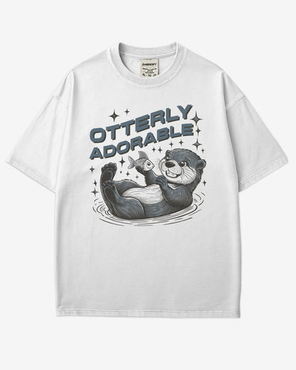 Flat lay white 'Otterly Adorable' shirt with a retro graphic of a happy otter holding a fish.