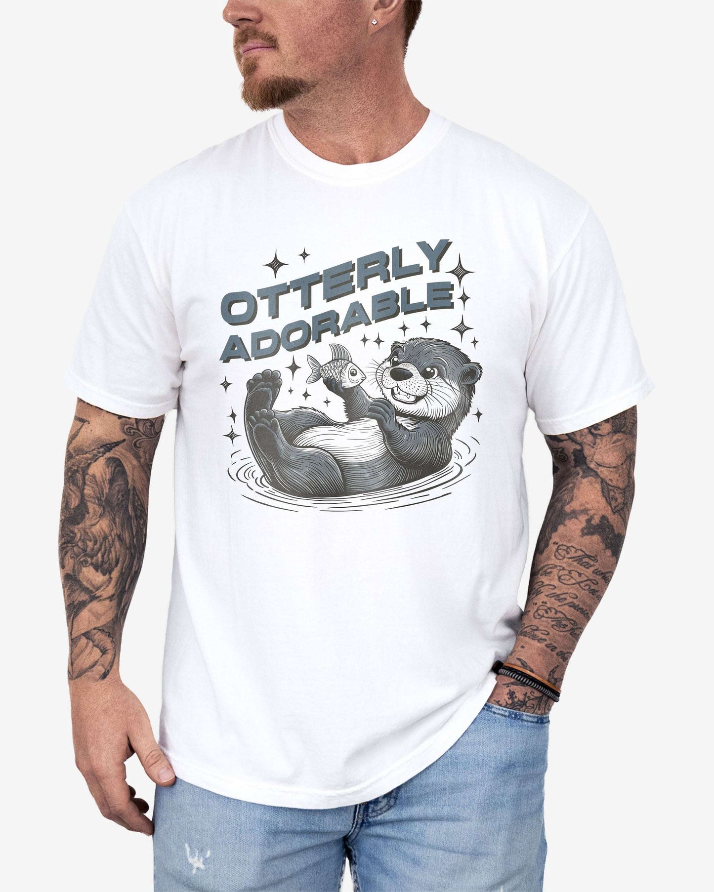 Man wearing a white 'Otterly Adorable' shirt with a retro graphic of a happy otter holding a fish.