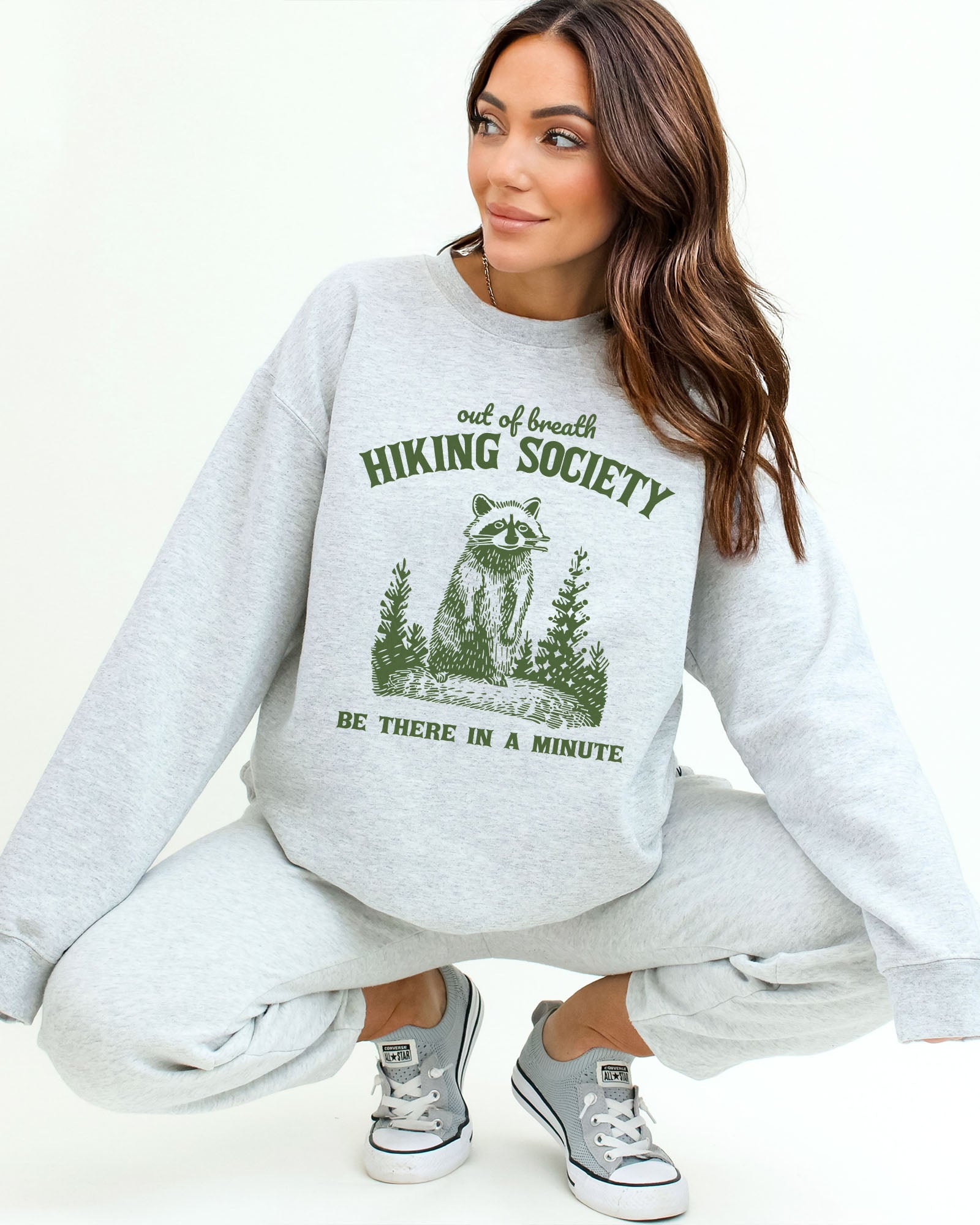 Model wearing ash color sweatshirt with 'Out Of Breath Hiking Society' graphic design