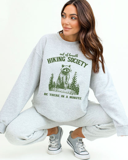 Model wearing ash color sweatshirt with 'Out Of Breath Hiking Society' graphic design
