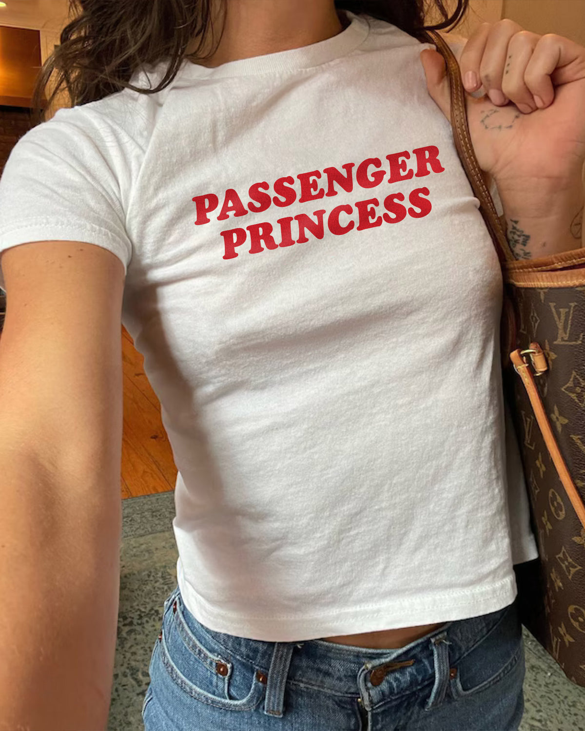 Woman wearing white y2k baby tee with retro text "Passenger Princess"
