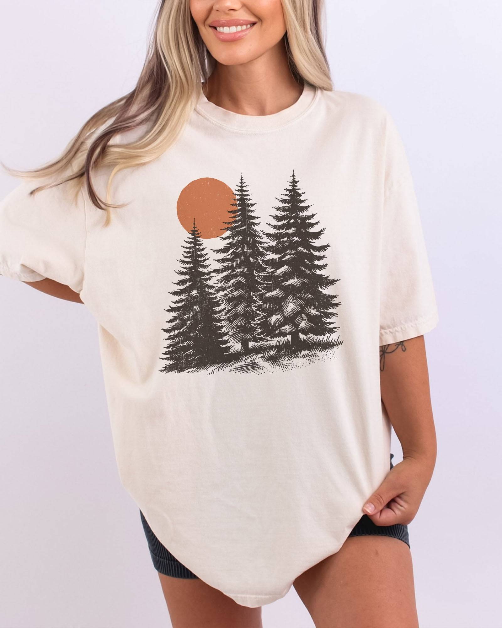 Model wearing ivory color shirt with pines and sun retro nature graphic design