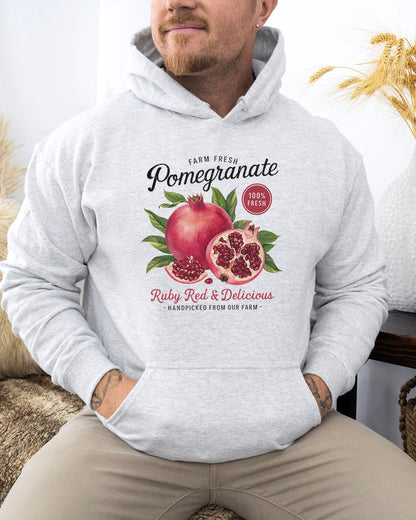 man wearing an ash hoodie featuring a vintage-style Pomegranate fruit label graphic with the text 'Pomegranate - Ruby Red & Delicious'.
