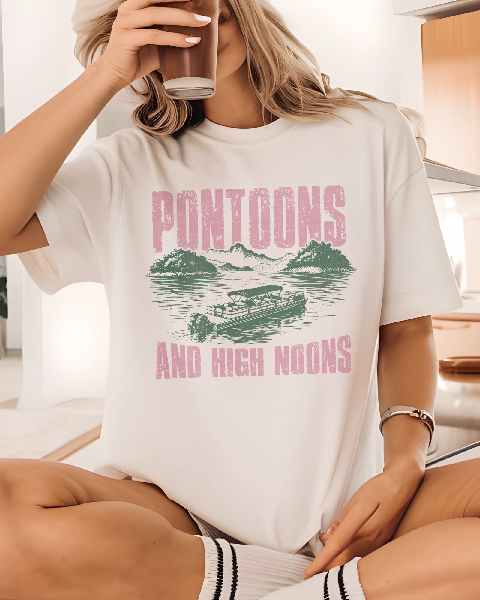 Woman wearing "Pontoons And High Noons" shirt in white color with a retro graphic of a pontoon on a lake.