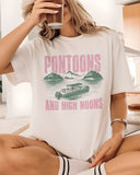 Woman wearing "Pontoons And High Noons" shirt in white color with a retro graphic of a pontoon on a lake.