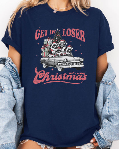 Woman wearing "Get In Loser We're Saving Christmas" shirt in navy blue color with a retro funny raccoon XMAS graphic
