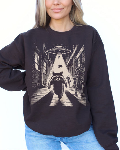 Woman wearing a dark chocolate sweatshirt with a retro graphic of a raccoon running from aliens.
