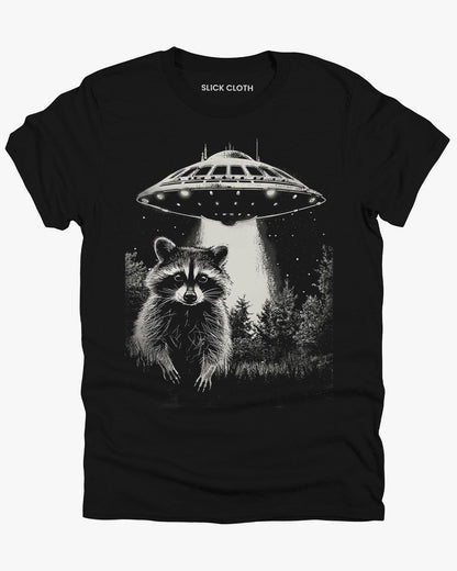 Flat lay black 'Raccoon UFO' t-shirt featuring a funny graphic of a raccoon escaping a UFO abduction.