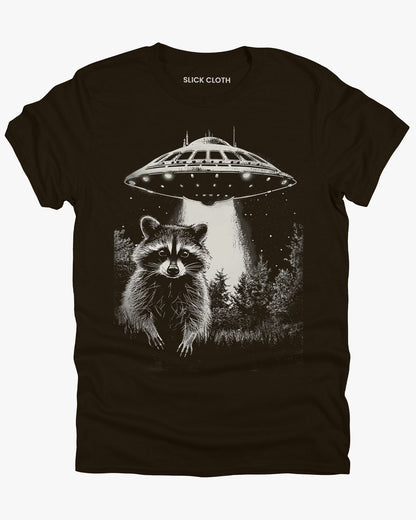 Flat lay dark chocolate 'Raccoon UFO' t-shirt featuring a funny graphic of a raccoon escaping a UFO abduction.
