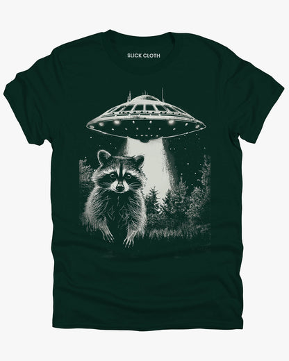 Flat lay forest green 'Raccoon UFO' t-shirt featuring a funny graphic of a raccoon escaping a UFO abduction.