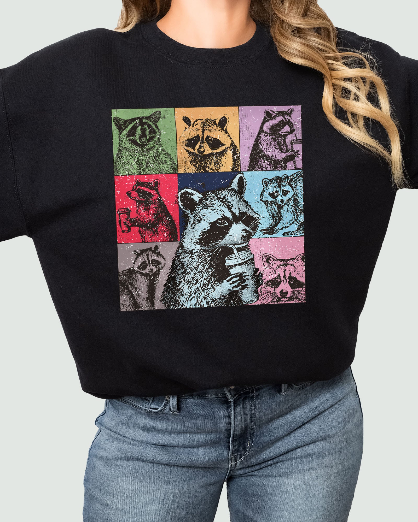 Woman wearing a sweatshirt in black, featuring a retro raccoons drinking coffee collage graphic design and unisex fit.