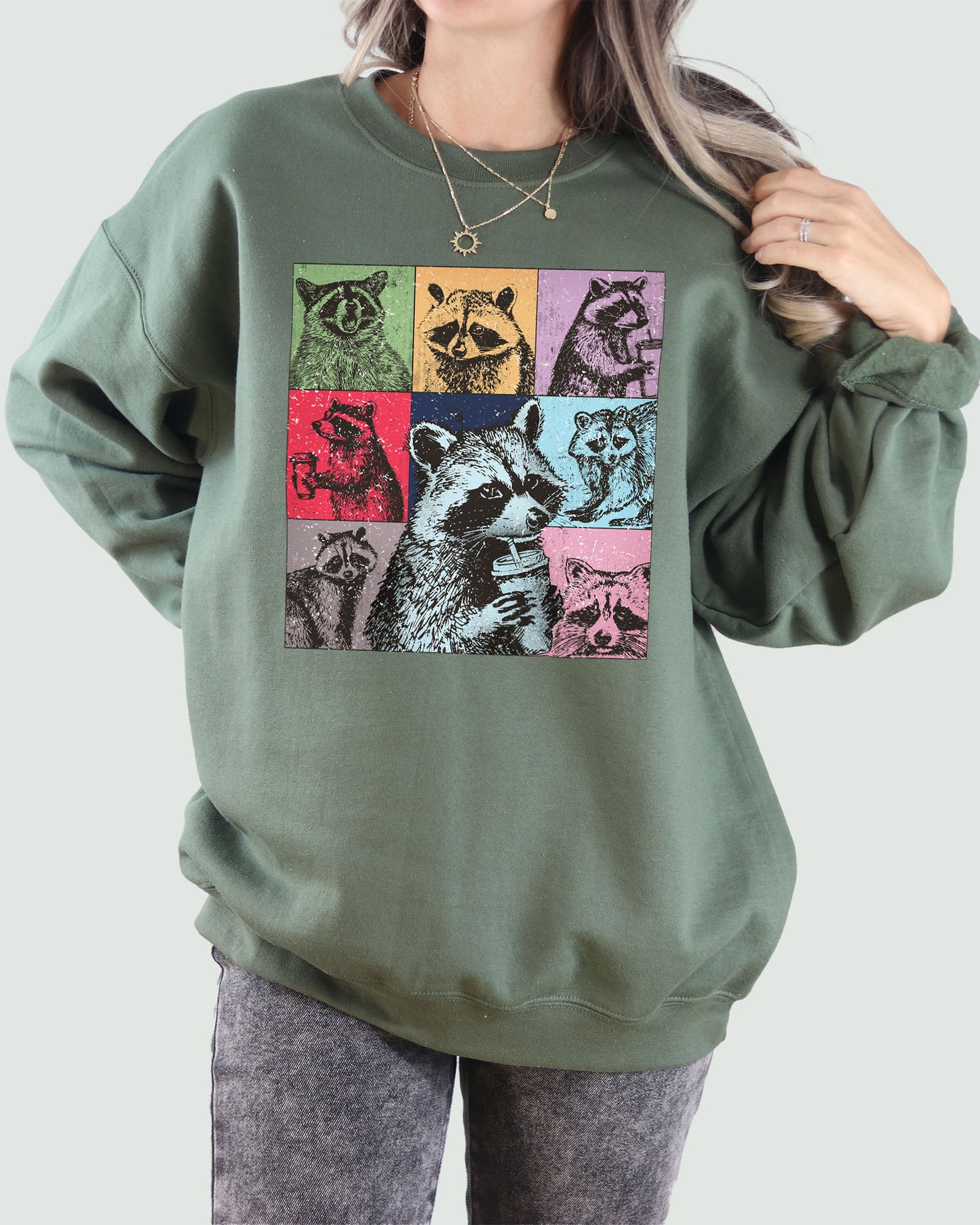 Woman wearing a sweatshirt in military green, featuring a retro raccoons drinking coffee collage graphic design and unisex fit.