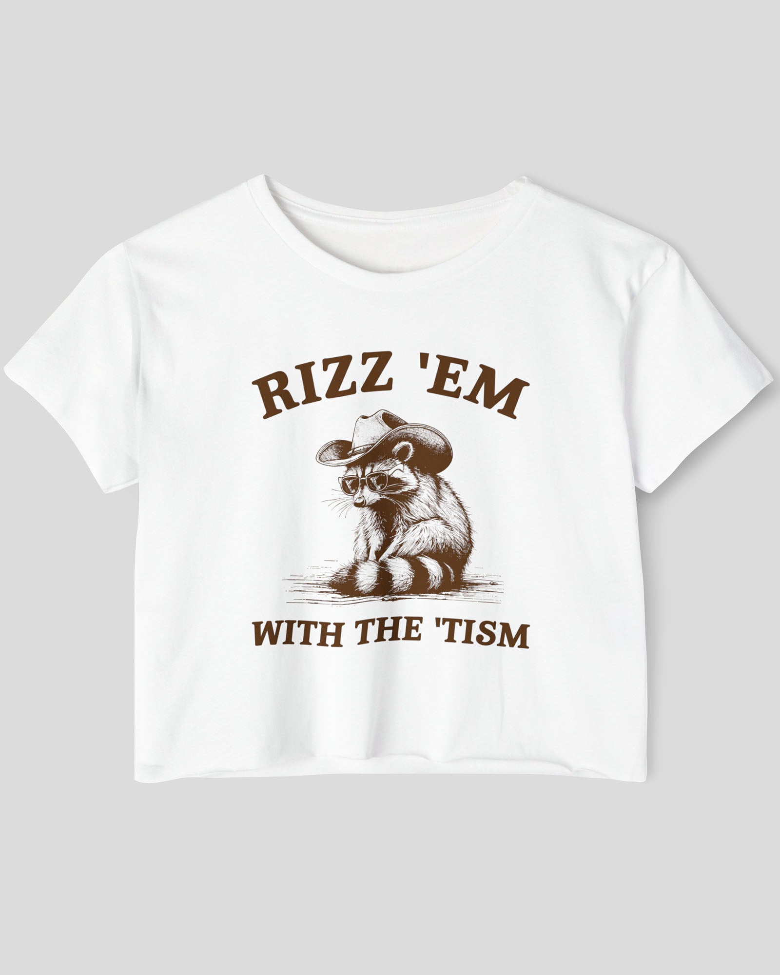 Flat-lay white 'Rizz Em With The Tism' crop top featuring a funny retro cowboy raccoon graphic.