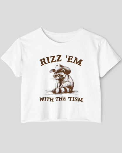 Flat-lay white 'Rizz Em With The Tism' crop top featuring a funny retro cowboy raccoon graphic.