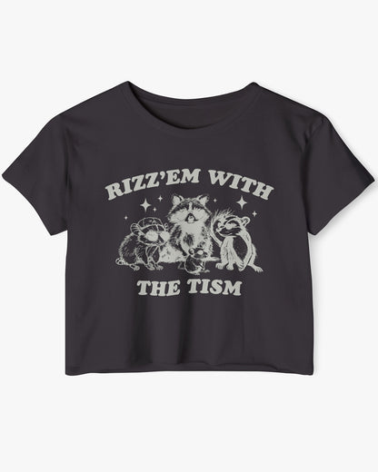 Flat lay black 'Rizz 'Em With The Tism' crop top featuring a funny retro raccoon gang graphic. Trendy women's graphic crop tee, retro aesthetic streetwear.