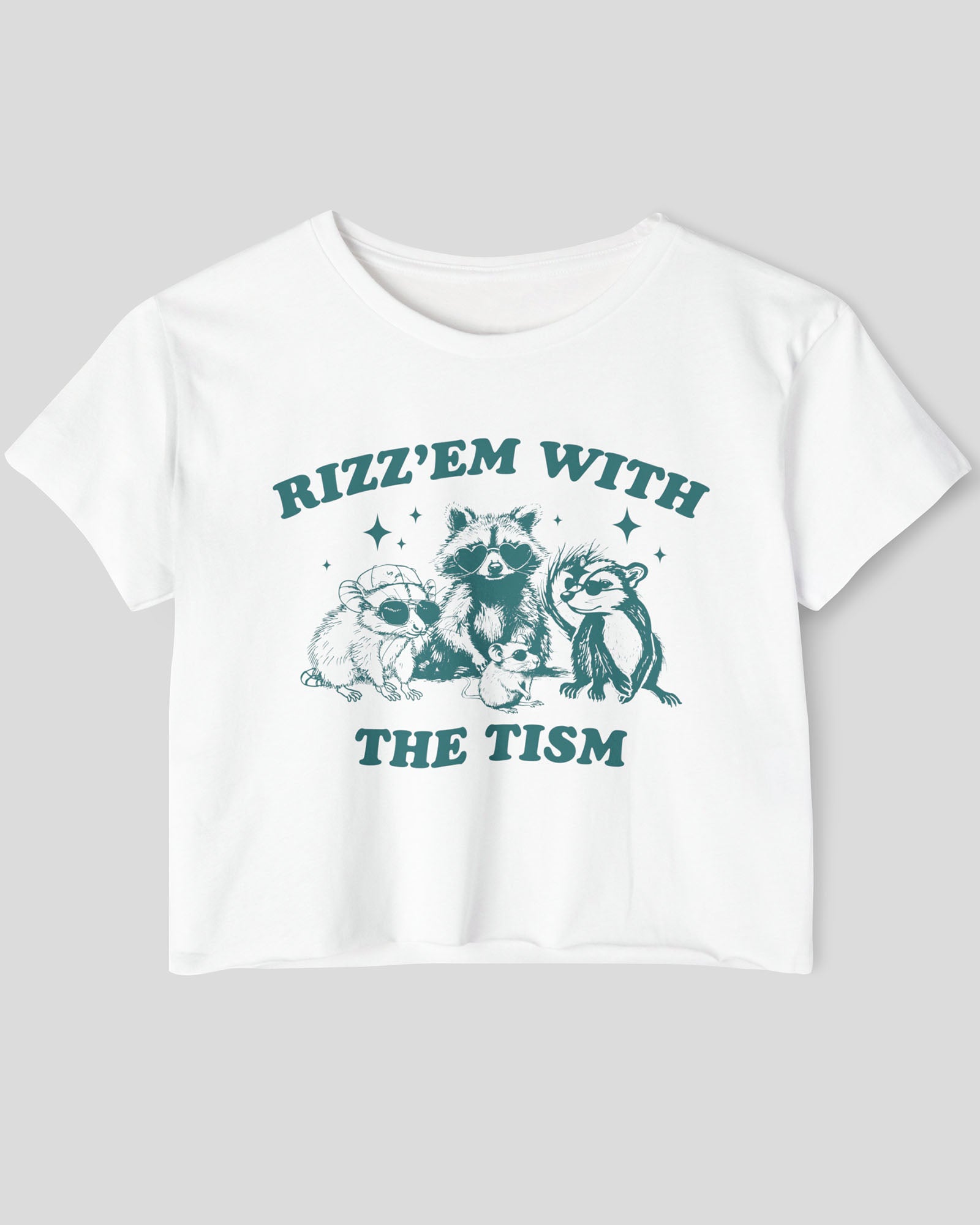 Flat lay white 'Rizz 'Em With The Tism' crop top featuring a funny retro raccoon gang graphic. Trendy women's graphic crop tee, retro aesthetic streetwear.