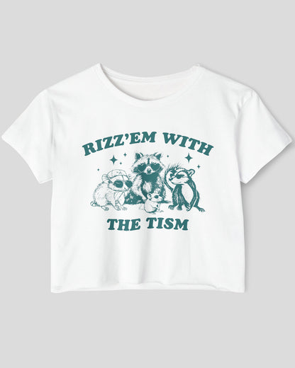 Flat lay white 'Rizz 'Em With The Tism' crop top featuring a funny retro raccoon gang graphic. Trendy women's graphic crop tee, retro aesthetic streetwear.