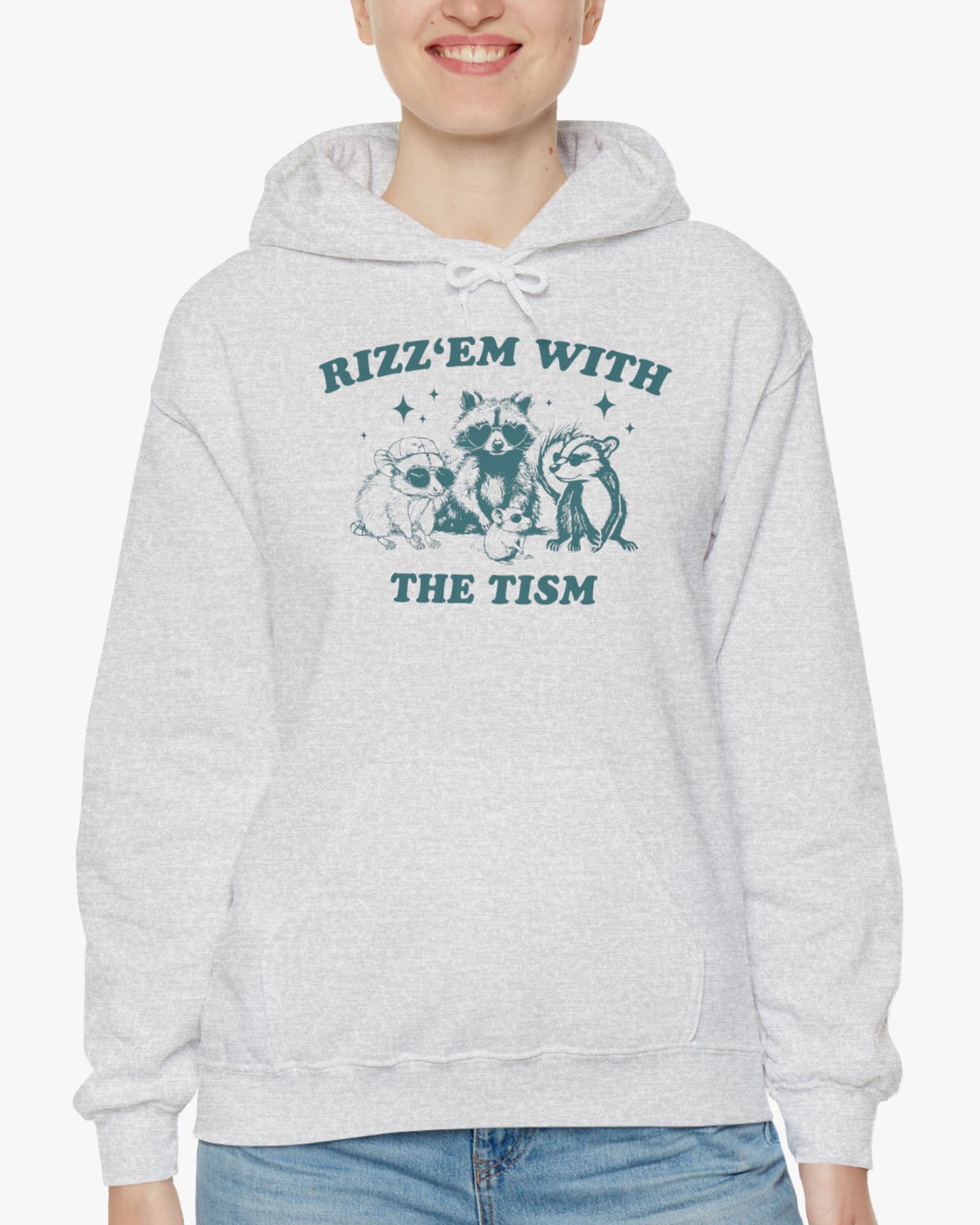 Woman wearing a 'Rizz Em With The Tism' hoodie in ash gray, featuring a retro western graphic design and unisex fit.