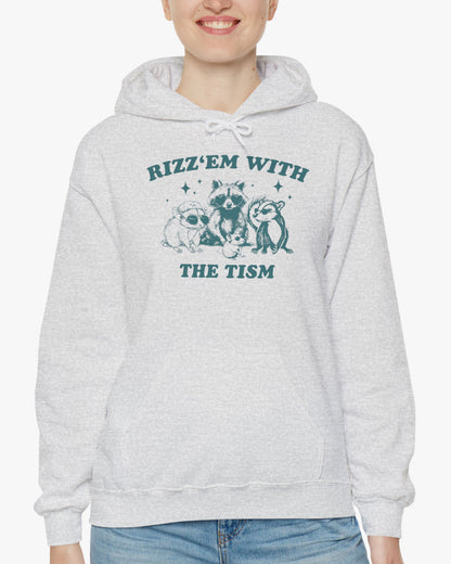 Woman wearing a 'Rizz Em With The Tism' hoodie in ash gray, featuring a retro western graphic design and unisex fit.