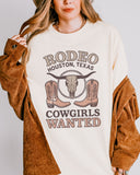 Woman wearing ivory color shirt with 'Rodeo Houston Texas Cowgirls Wanted' graphic design