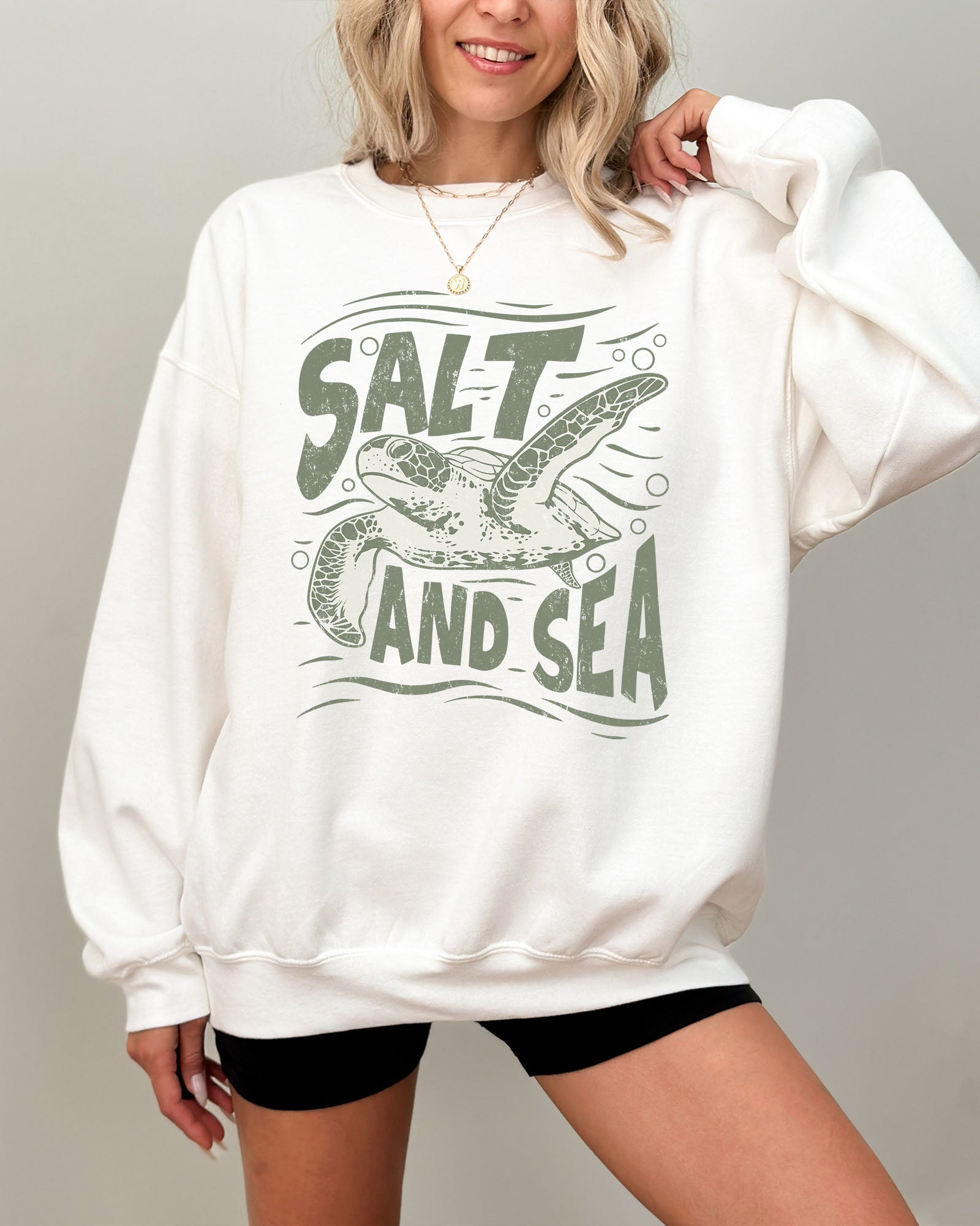 Model wearing white color sweatshirt with 'Salt And Sea' graphic design