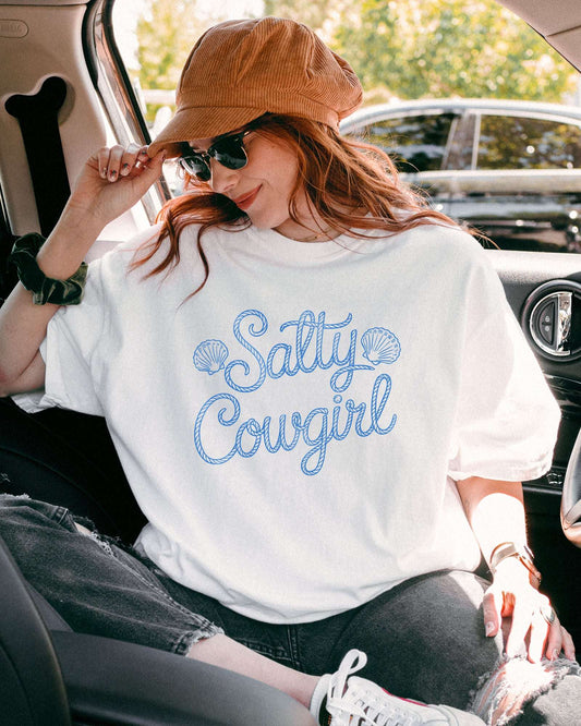 Woman wearing a white 'Salty Cowgirl' shirt.