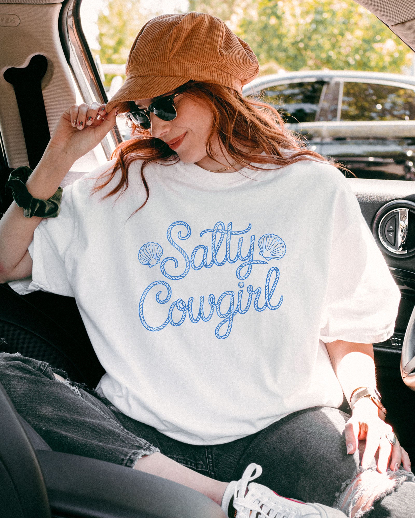 Woman wearing a white 'Salty Cowgirl' shirt.