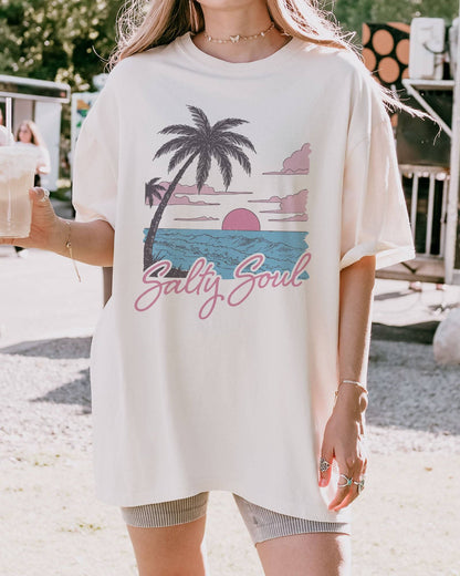 Model wearing ivory color shirt with 'Salty Soul' funny retro beach graphic design