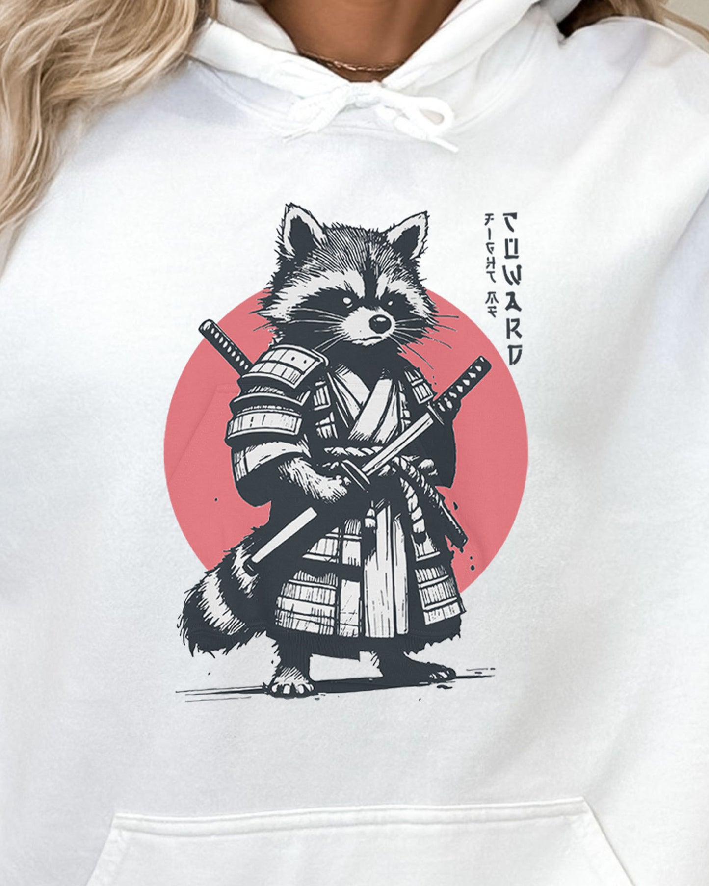 Close-up of white hoodie featuring a retro funny samurai raccoon graphic with the quote 'Fight Me Coward' in a Japanese-style font.