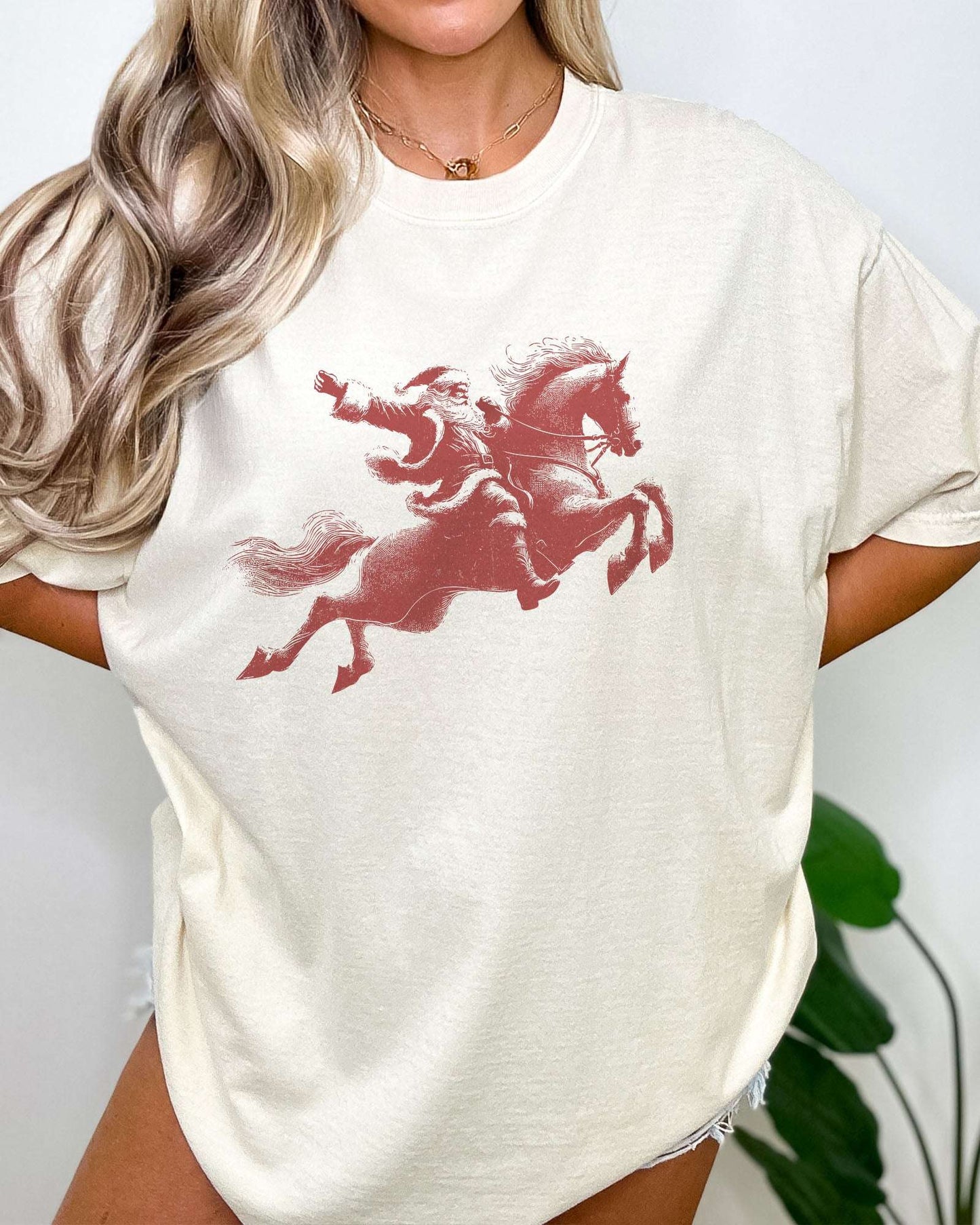 Model wearing ivory color shirt with 'Santa Riding A Horse' graphic design