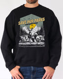 Man wearing a black sweatshirt with a retro wildlife design featuring animals lined up in a park and the quote 'Save Our Parks – Resist, Defend, Protect'.